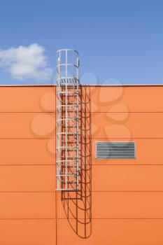Modern industrial building wall with metal ladder,under blue sky