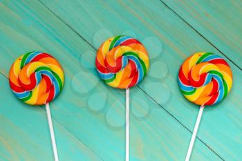 Three colorful  lolly pops on blue wooden background