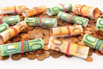 Pile of Euro cents with banknote rolls on top