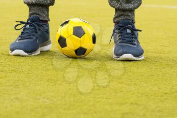 Feet of player with ball on artificial turf soccer field 