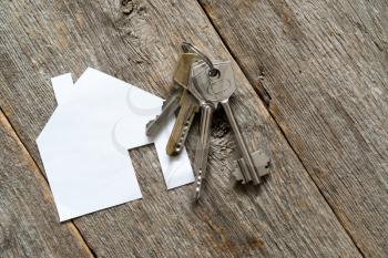 House icon and keys on wooden background. Concept for real estate or renting home.