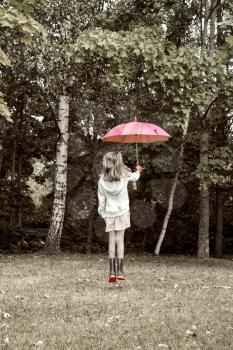 Young girl jump with umbrella against park trees