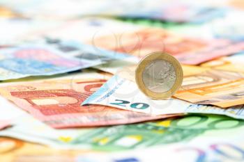 Euro coin balancing on Euro banknotes background