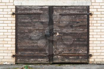 Old wooden garage door with padlock and hinges