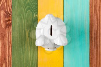 White piggy bank on color wooden background, top view