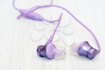 Purple earphones on wooden background, close-up view. The concept of music, sports, active lifestyle.
