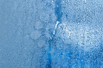 Background of the condensate flowing water on the window glass