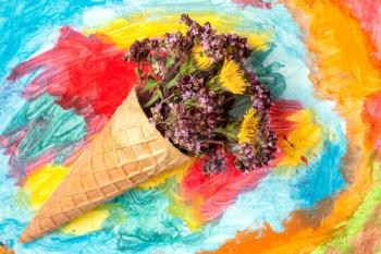 Flowers in a wafer cone on a painted background. Flat lay, top view.