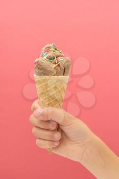 Ice cream cone in hand on pink bright background. Summer desserts.