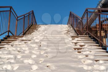 Snow covered stairs with stainless steel banister or handrails for pedestrians