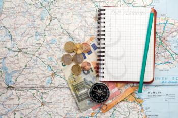 Travel concept with notebook written TRIP PLANNING , compass and money on the  map 