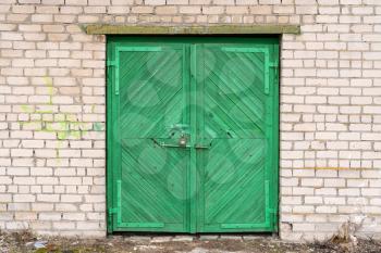Green wooden garage door on brick wall
