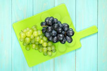 Plastic cutting board with green and blue grapes
