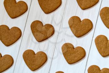 Heart shaped gingerbread cookies on white wooden background