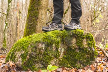 Hiker stands on the mossy stone in the forest. Tourism or active life concept
