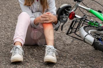 Girl in pain after a bicycle accident. Kids safety concept