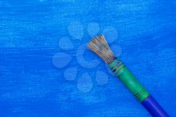 Paint brush on a blue painted canvas. Copy space