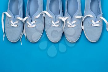 Row of soft blue color canvas shoes on blue background