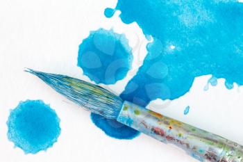 Paintbrush and splatter of blue watercolor. Close-up view.