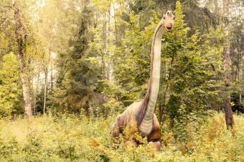 Statue of Branchiosaurus dinosaur in a green forest
