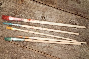 Set of dirty paint brushes on wooden background