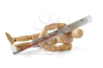 Fallen wooden man holding thermometer indicating a high temperature. Cold, virus and flu season concept.