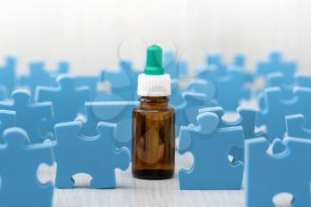 Glass bottle with medicine or essential oil surrounded by puzzle pieces