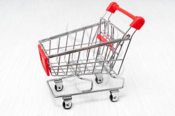 Empty shopping cart on wooden background. Purchase or marketing concept