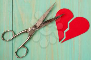 Paper red heart cuted by scissors. The concept of divorce, separation, quarrel.