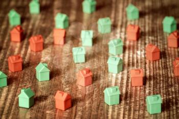 Red and green plastic toy houses on a wooden background.Real estate concept.