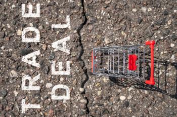 Asphalt crack between shopping cart and words TRADE DEAL