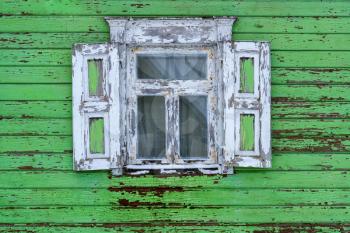 Old, abandoned wooden house wall with window and cracked paint