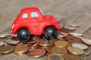Saving for a new car. Red car on a pile of coins