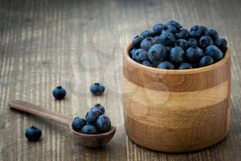 Organic blueberries in wooden bowl on wooden background. Healthy eating and nutrition.