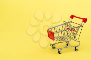 Empty shopping cart on yellow background. Purchase or marketing concept