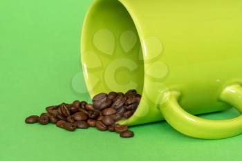 Coffee beans spilling out of a green cup