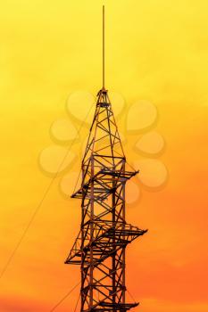 Electricity pylon at orange sunset.Silhouette of High voltage electric tower on the sunset time