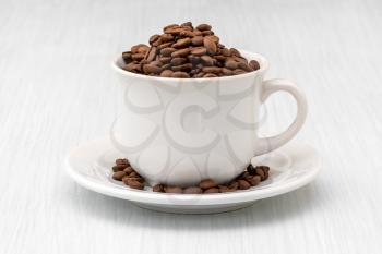 Cup full of coffee beans on the white wooden table