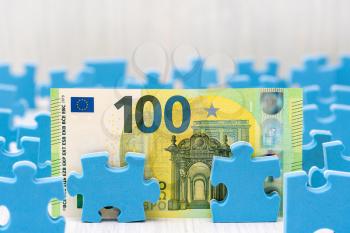 One hundred Euro surrounded by puzzle pieces, understanding the ins and outs of investing