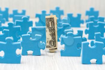 One dollar surrounded by puzzle pieces, understanding the ins and outs of investing