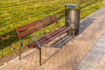 Wooden bench and trash can in the city park. Modern urban style of public place.