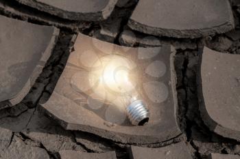 Light bulb glowing in the desert. Concept power solar energy in nature