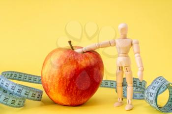 Healthy life concept with wooden mannequin, red apple andmeasure tape