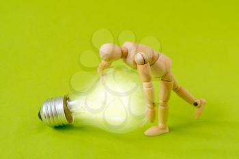 Wooden doll raising a glowing light bulb. Business and Innovative idea concept.