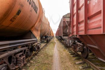 Walking between two cargo trains. Railway station with freight trains