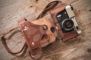 Old film camera lying on the wooden background. Top view.