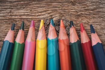 Colored pencil crayons on the wooden background, close-up view
