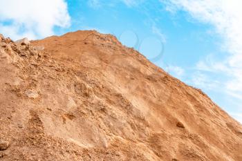 Heap in the quarry sand against the blue sky background