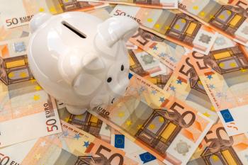 Piggy Bank surrounded by banknotes of fifty Euro