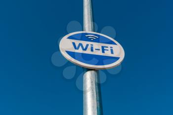 Wireless internet sign on pole on the street against blue sky background